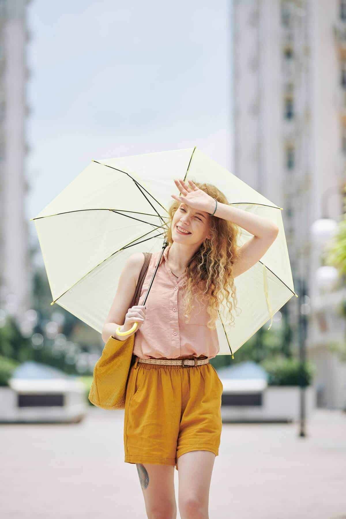 Kobieta chowająca się pod parasolem w upalny dzień