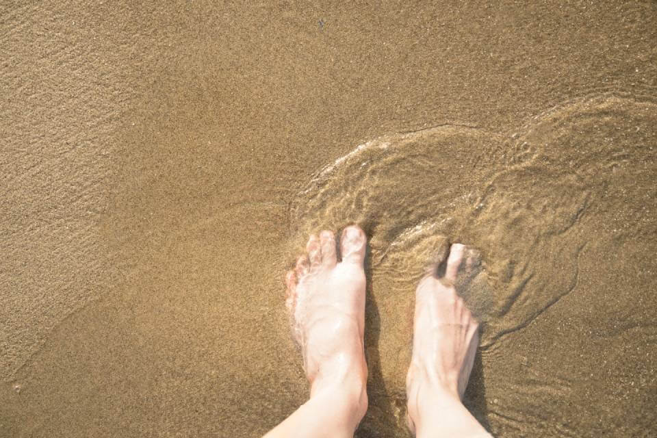 Stopy zanurzone w miękkim piasku na słonecznej plaży